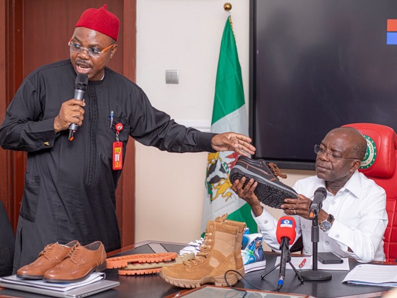 Governor Otti scrutinises a sample of one of the shoes produced by Comfort Stevens, presented to him by Dr. John Nwankwo.
