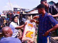 Dr Betta Edu (middle) handing poverty alleviation food items to a male beneficiary. 
