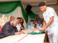 Abia State Governor, Dr. Alex Otti, signing the Dig Once Policy document after it was presented to him by the Commissioner for Digital Economy and SMEs, Dr. Matthew Ekwuribe (right).