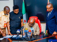Governor Otti signing the new law that has repealed the payment of pensions to former governors and their deputies. The Governor is keenly watched by the Attorney-General and Commissioner for Justice, Mr. Ikechukwu Uwanna (right); the Deputy Speaker, Rt Hon Austin Okezie Nmeregini (second left) and Clerk of the House, John-Pedro Irokansi.